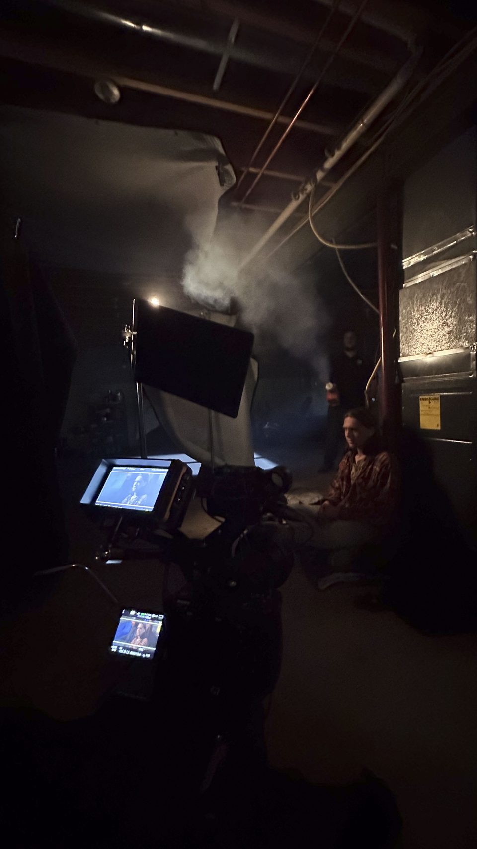 A camera operator framing a shot in low light.